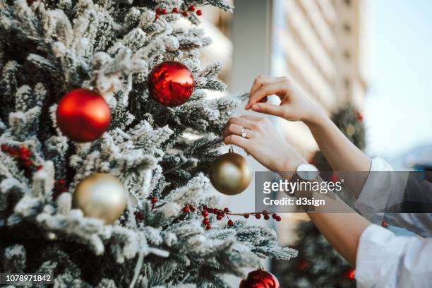 cropped hand of woman decorating and hanging baubles on christmas tree - decoration stock pictures, royalty-free photos & images