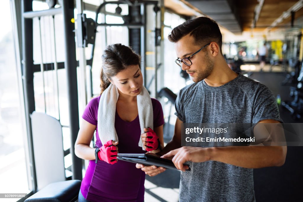 Woman and personal trainer making exercise plan in gym