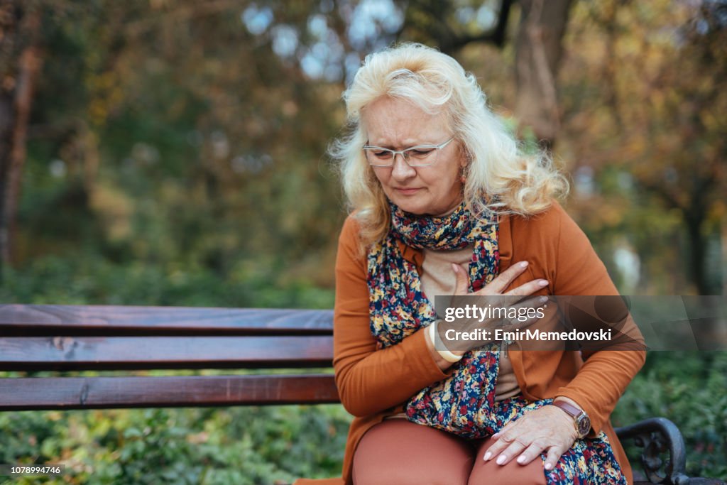 Ältere Frau mit Schmerzen in der Brust oder Herzinfarkt im Park