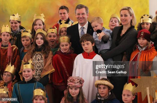 German President Christian Wulff and his wife Bettina, who is holding their son Linus pose with child Epiphany carolers at Bellevue Presidential...