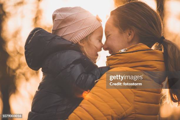 happy girl in mother's arms at sunset - yellow hat stock pictures, royalty-free photos & images