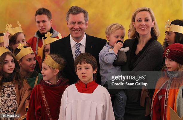 German President Christian Wulff and his wife Bettina, who is holding their son Linus pose with child Epiphany carolers at Bellevue Presidential...