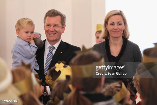 German President Christian Wulff, who is holding his son Linus and his wife Bettina receive child Epiphany carolers at Bellevue Presidential Palace...