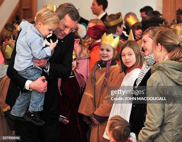 German President Christian Wulff holds his two-year-old son Linus as he speaks with carol singers from the Hamburg area during a reception at the...