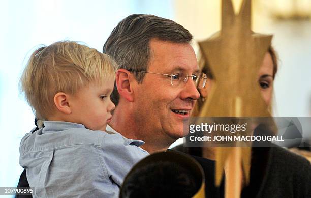 German President Christian Wulff holds his two-year-old son Linus as he and his wife Bettina Wulff speak with carol singers from the Hamburg area...