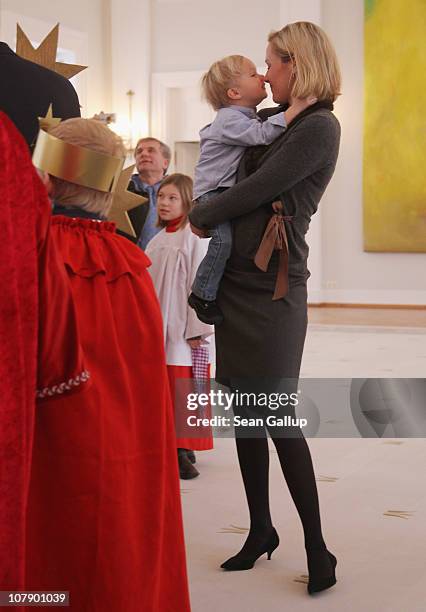 German First Lady Bettina Wulff carries her son Linus at a reception for child Epiphany carolers at Bellevue Presidential Palace on January 6, 2011...