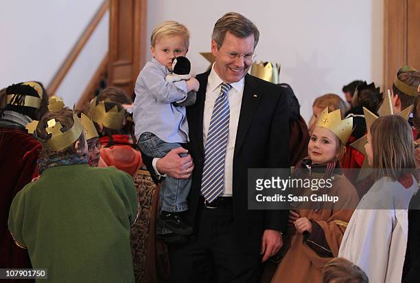 German President Christian Wulff, who is holding his son Linus receives child Epiphany carolers at Bellevue Presidential Palace on January 6, 2011 in...