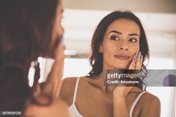 woman doing skin care routine at home - mid adult women stock pictures, royalty-free photos & images
