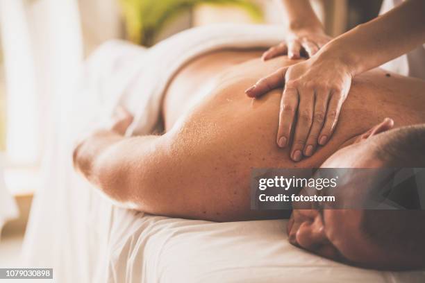 man getting shoulder massage by a professional therapist - man massage stock pictures, royalty-free photos & images