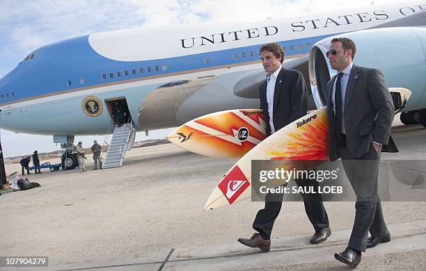 White House staffers Ben Finkenbinder and Nick Shapiro carry surfboards as they walk away from Air Force One after arriving with US President Barack...