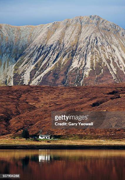 cottage by mountains reflected in a loch - cuillins stock-fotos und bilder