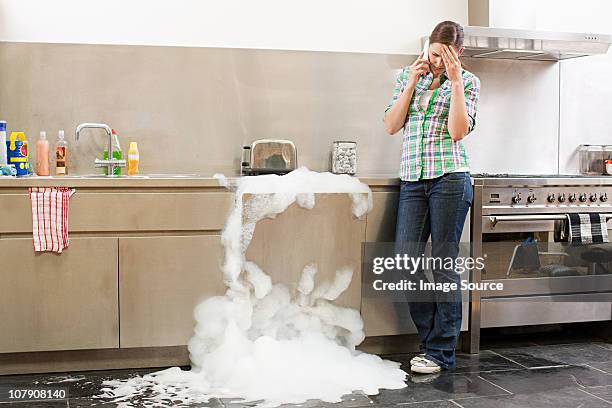 young woman on phone with overflowing dishwasher - untidy sink stock pictures, royalty-free photos & images