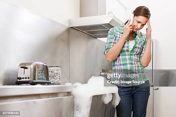 young woman on phone with overflowing dishwasher - plug hole stock pictures, royalty-free photos & images