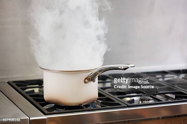 saucepan boiling on hob with steam - gaskookplaat stockfoto's en -beelden