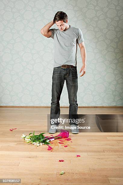 young man with broken vase of flowers on floor - broken vase stock pictures, royalty-free photos & images