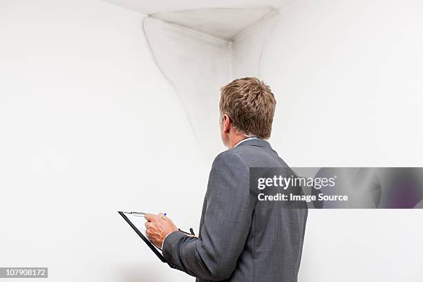 mature man examining damp patch on wall - nat stockfoto's en -beelden