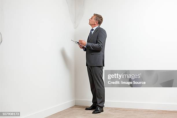 mature man examining damp patch on wall - man check suit stock pictures, royalty-free photos & images