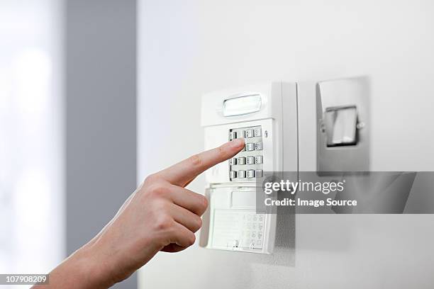 woman setting burglar alarm - alarm stockfoto's en -beelden