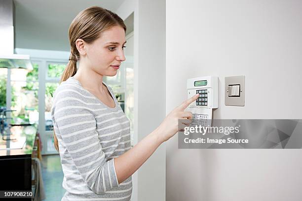 woman setting burglar alarm - alarm system stock pictures, royalty-free photos & images