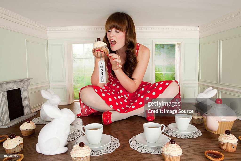 Young woman eating cake at tea party in small room