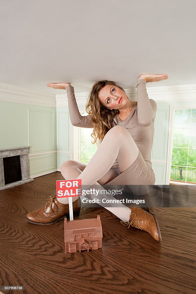 Young woman in small house with model of house for sale