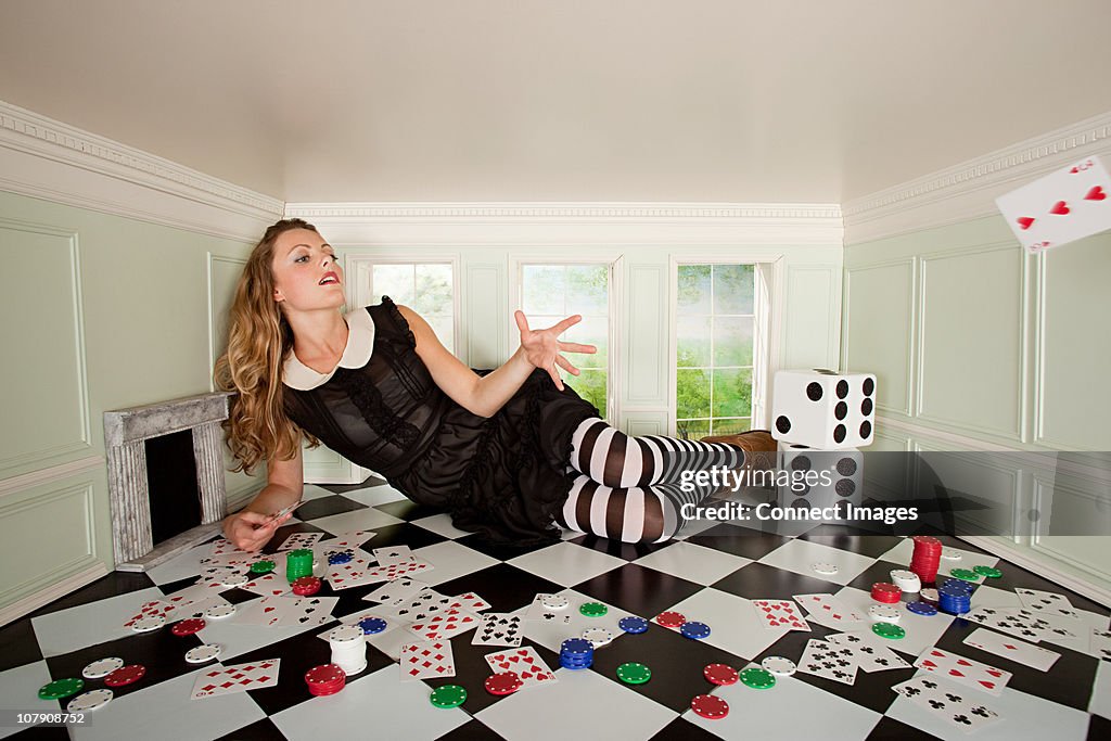 Young woman in small room throwing playing card