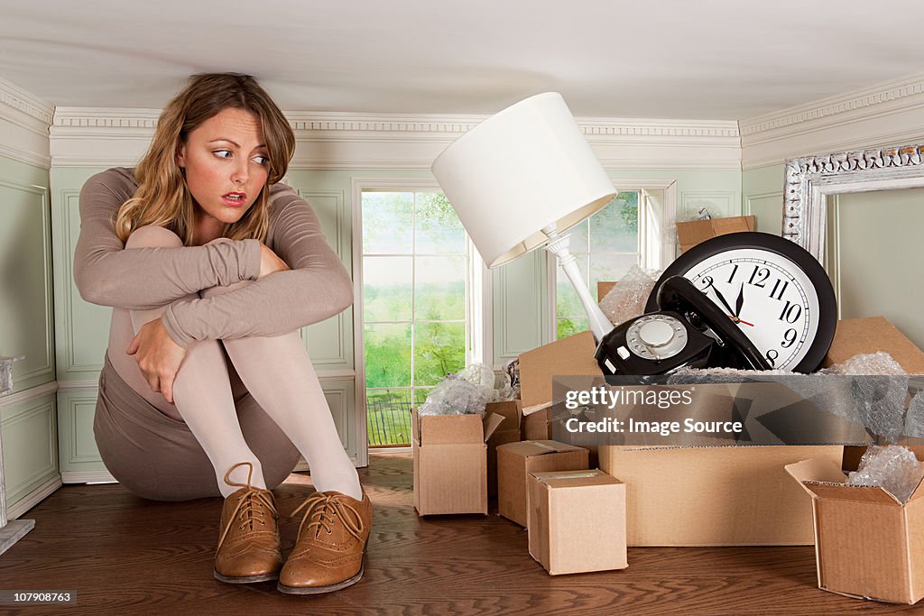 Young woman with box of objects in small room