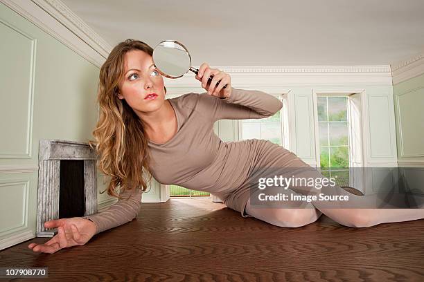 young woman in small room with magnifying glass - looking through a doll house foto e immagini stock
