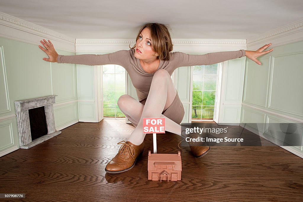 Young woman in small house with model of house for sale