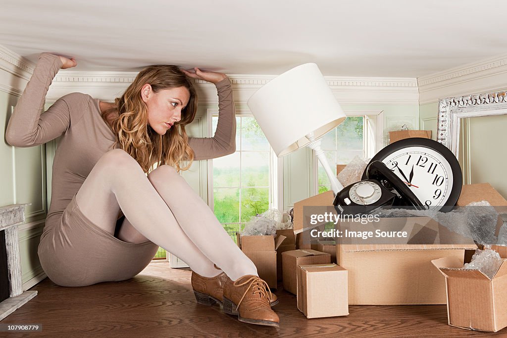 Young woman with box of objects in small room