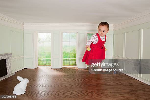 toddler girl in a tiny room, looking at rabbit - giant rabbit photos et images de collection