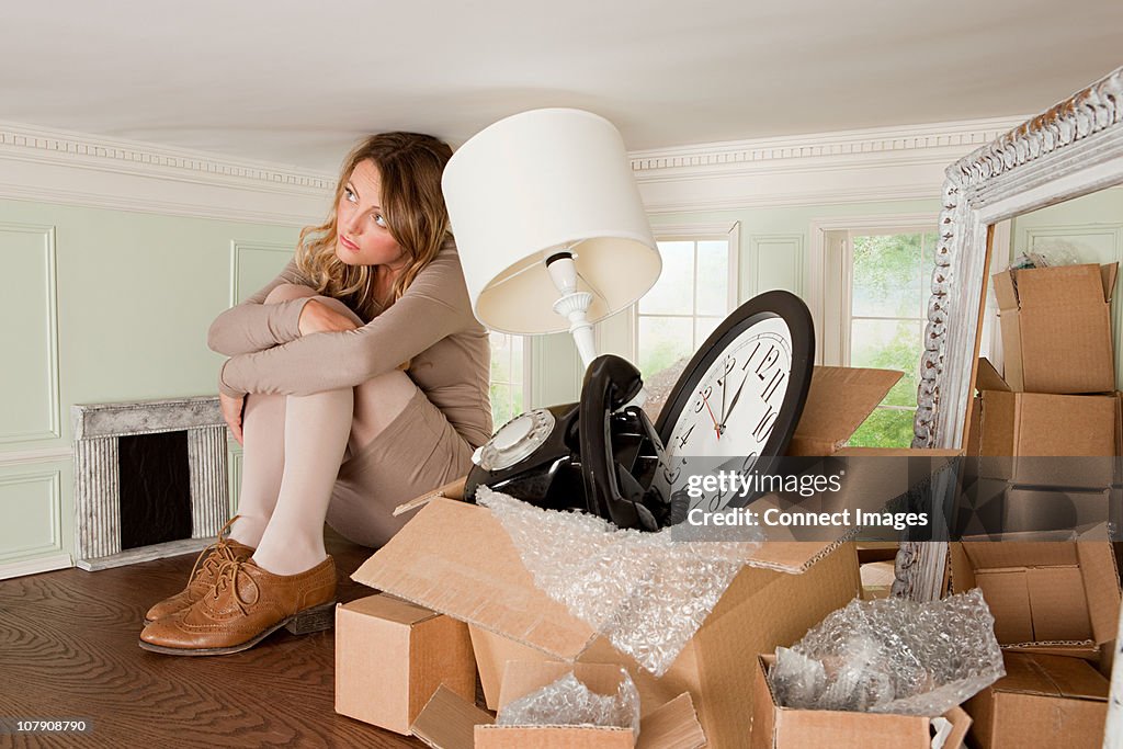 Young woman with box of objects in small room