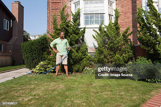 hombre con hosepipe riego de césped - jardín de delante fotografías e imágenes de stock