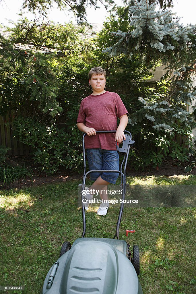 Boy mowing grass with lawnmower