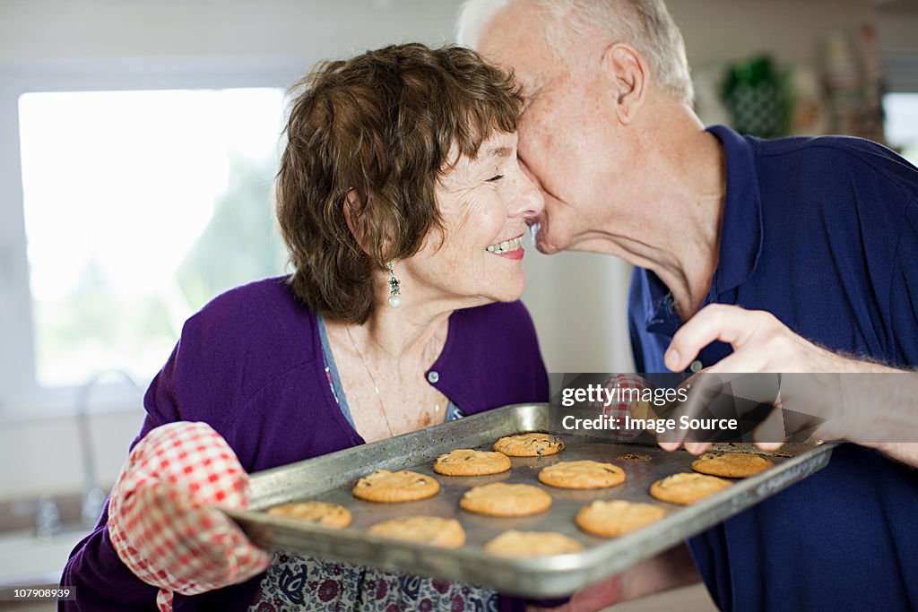 Senior couple kissing with home baked cookies