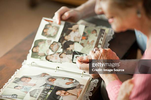 senior couple looking at family album - erinnerung stock-fotos und bilder