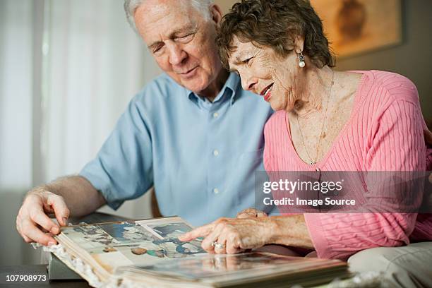 senior couple looking at family album - looking at a photo album stock-fotos und bilder