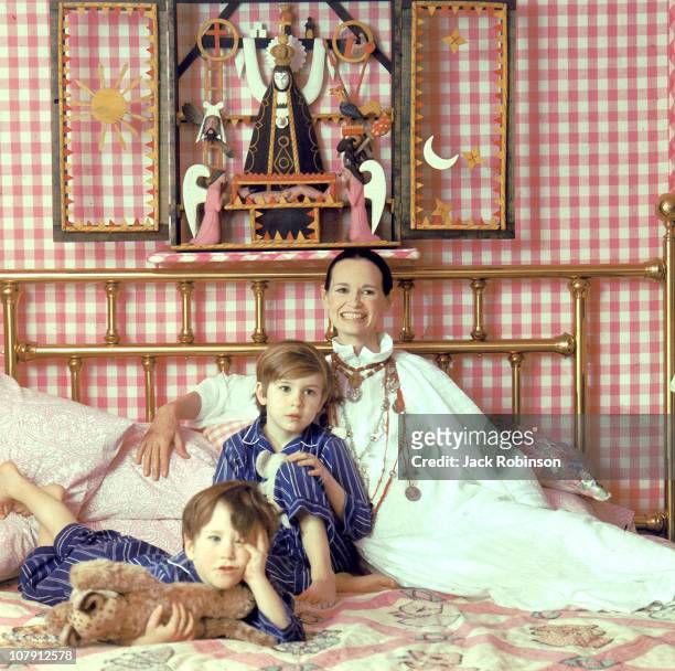 Socialite and heiress Gloria Vanderbilt poses for a portrait session with her sons Anderson Cooper and Carter Vanderbilt Cooper on a bed in their...