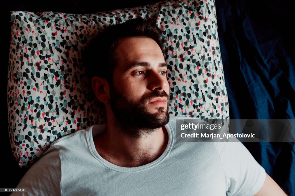 Young man lying in bed thinking