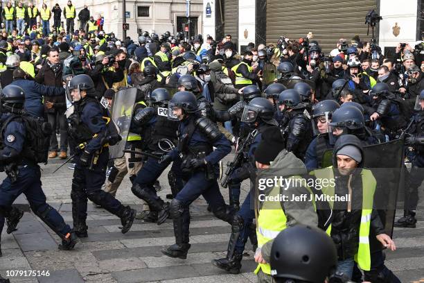 French police charge as demonstrators take part in the demonstration of the yellow vests near the Arc de Triomphe on December 8, 2018 in Paris...