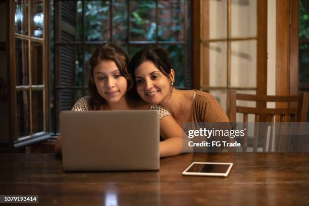 niña usando laptop con tu madre en casa - ethnicity fotografías e imágenes de stock