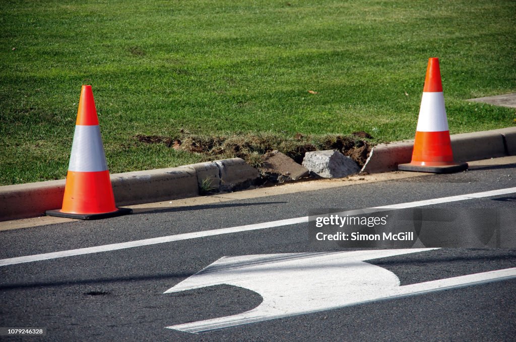 Broken concrete road curb and traffic cones
