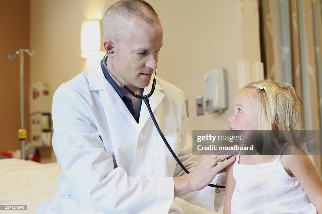 Young pediatrician listens to young girl's breathing