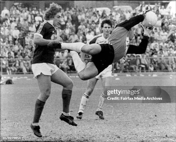 Footscray goalkeeper Dennis Boland thwarts another Olympic attack as he sails out of goal to take the ball before Olympic can pounce. Footscray's...