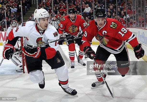 Chris Campoli of the Ottawa Senators and Jonathan Toews of the Chicago Blackhawks chase after the puck as Viktor Stalberg of the Blackhawks stands...