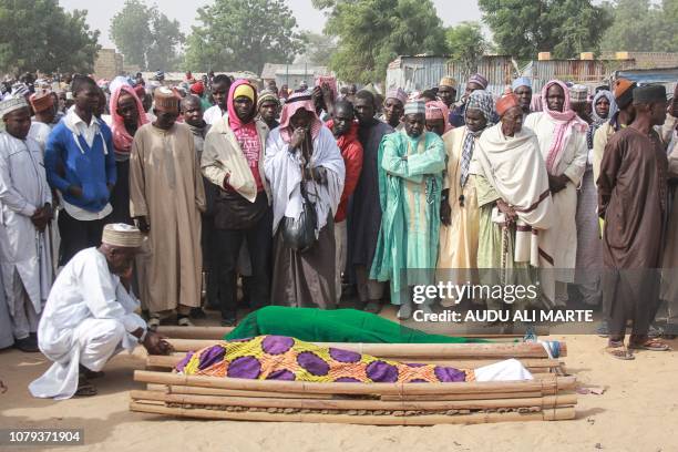 People gather around the corps of attack victims during their burial ceremony at the Sajeri village on the outskirts of the Borno state capital,...