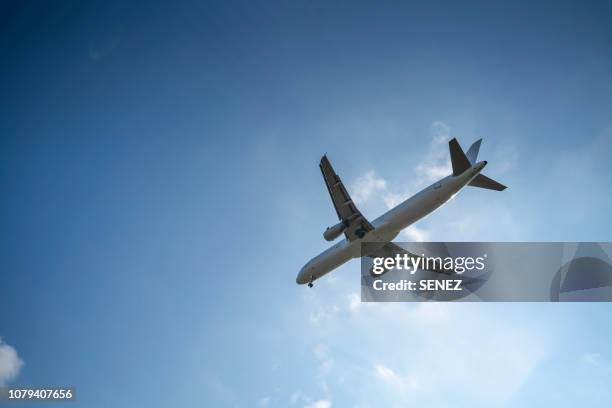 directly below shot of airplane flying in sky - captains day stock-fotos und bilder