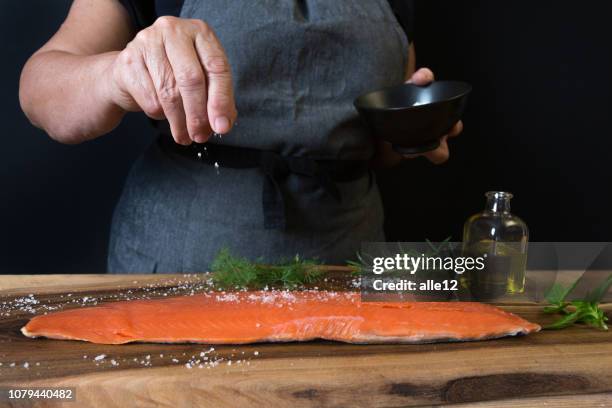 mulher, adição de sal sobre o salmão - sal de cozinha - fotografias e filmes do acervo