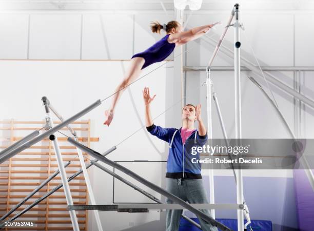 trainer guiding young gymnast on parallel bars - uneven parallel bars stock pictures, royalty-free photos & images
