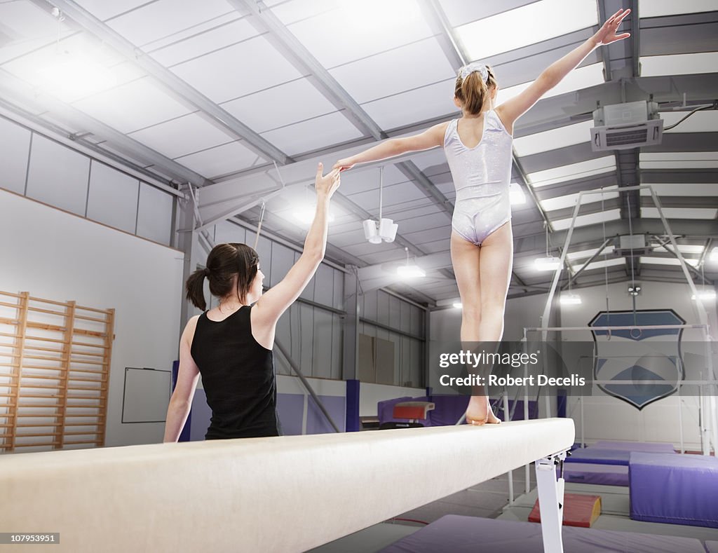 Trainer assisting young female gymnast